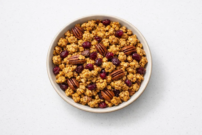 Bowl of Christmas granola with gingerbread spices, pecans, and dried cranberries