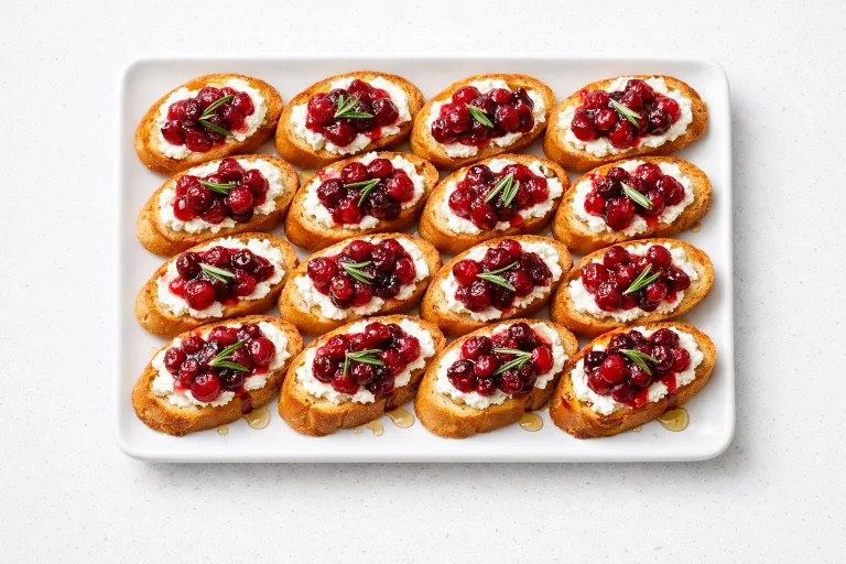Christmas bruschetta with cranberry compote and goat cheese on a white serving platter
