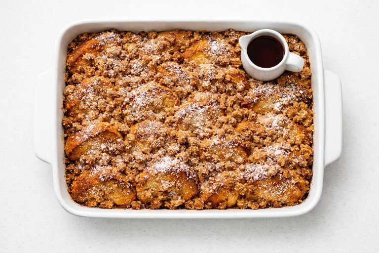 Christmas French toast bake in a white baking dish with golden streusel topping and powdered sugar, ready to serve on Christmas morning
