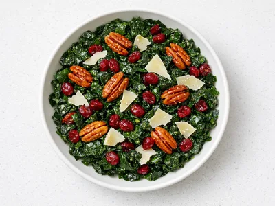 Christmas kale salad with cranberries, candied pecans, and shaved parmesan in a white bowl