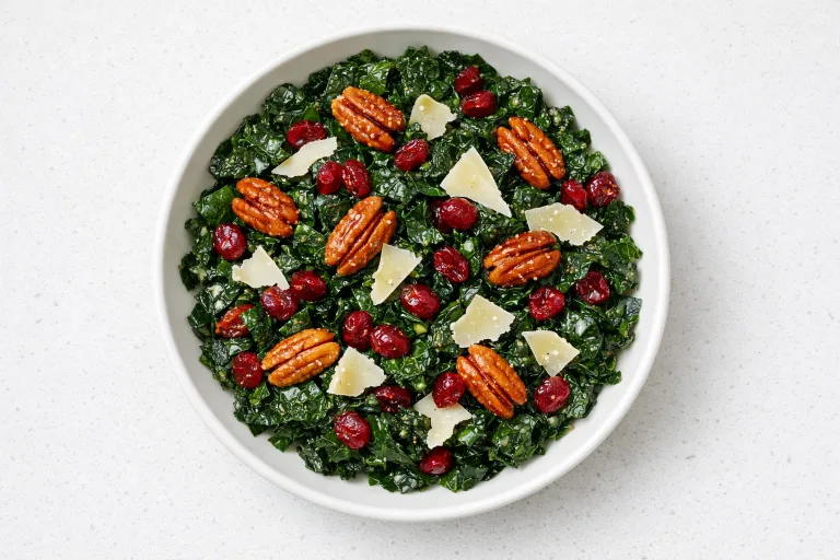 Christmas kale salad with cranberries, candied pecans, and shaved parmesan in a white bowl