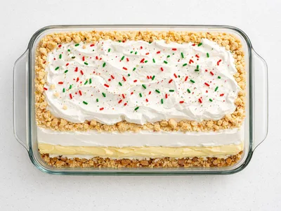 Christmas lush layered dessert in a glass baking dish with whipped topping and holiday sprinkles
