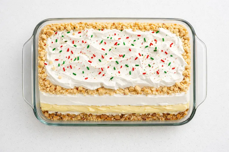Christmas lush layered dessert in a glass baking dish with whipped topping and holiday sprinkles