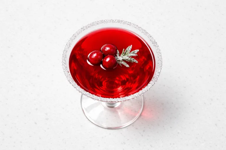 Christmas martini cocktail in a crystal glass with cranberry and rosemary garnish