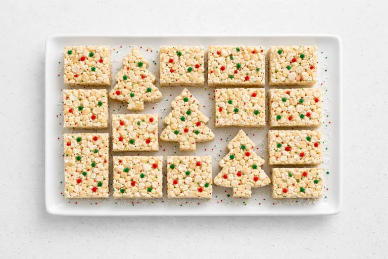 Christmas Rice Krispie treats with red and green sprinkles cut into squares on a white platter
