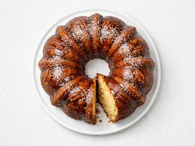 Christmas rum cake bundt with buttered rum glaze and powdered sugar on a white cake stand