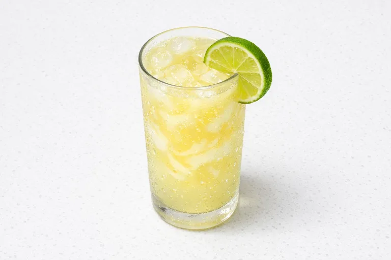 Classic British snowball cocktail in a highball glass with advocaat and lemonade, lime slice on the rim
