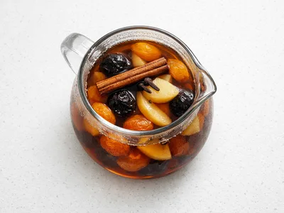 Czech Christmas kompot with dried fruit, cinnamon stick, and cloves in a glass pitcher