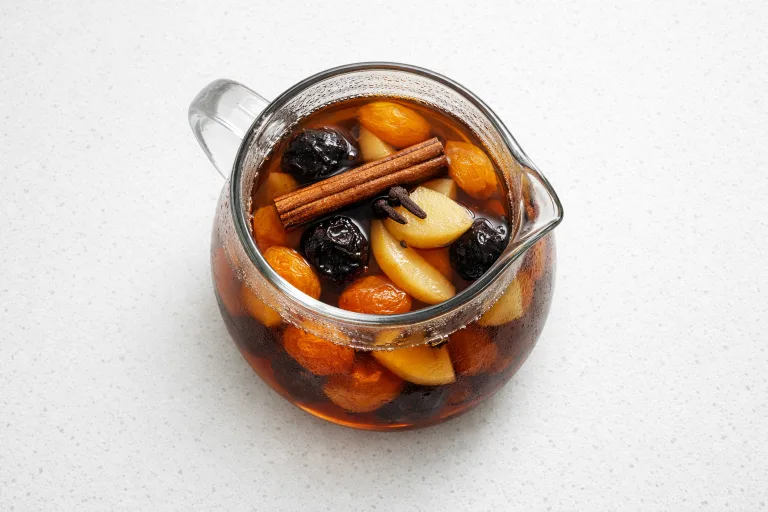 Czech Christmas kompot with dried fruit, cinnamon stick, and cloves in a glass pitcher