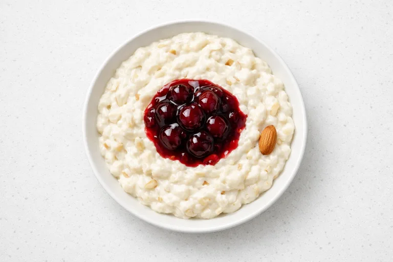 Danish risalamande rice pudding in a white bowl with cherry sauce and whole almond
