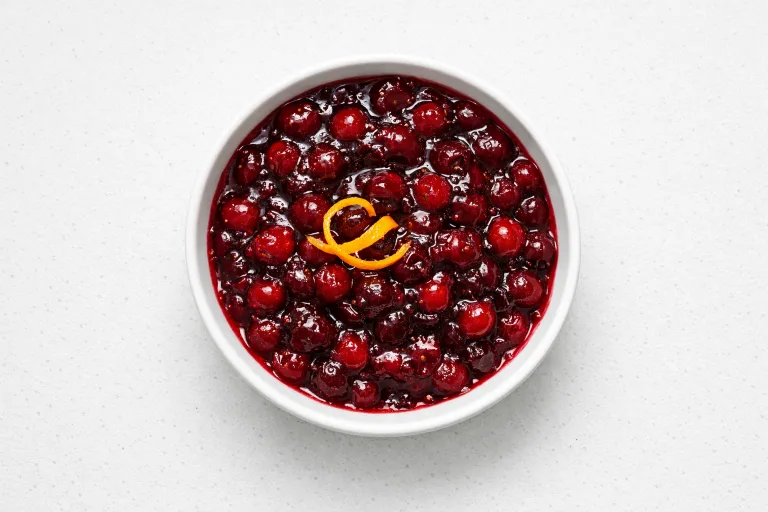 Homemade whole-berry cranberry sauce in a white bowl with orange zest
