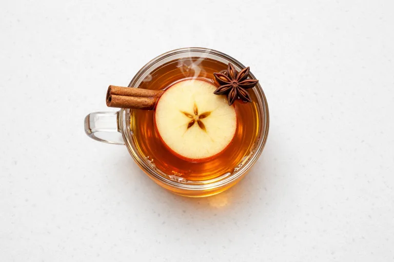 Hot chai apple cider in a glass mug with cinnamon stick and star anise, steam rising