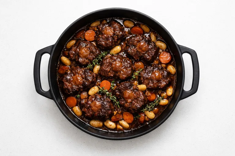 Jamaican braised oxtails in a cast iron pot with butter beans and thyme
