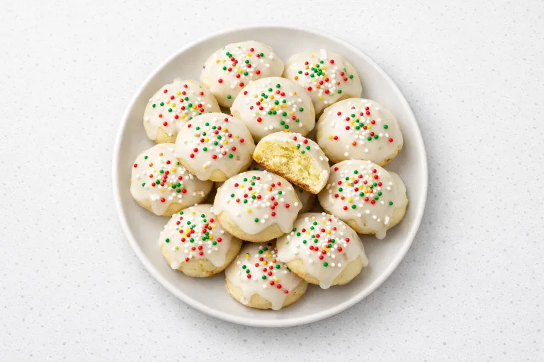 Plate of soft Italian Christmas cookies with lemon glaze and rainbow sprinkles