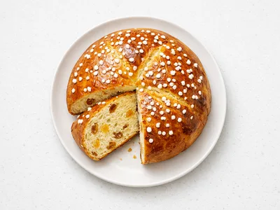 Sliced Norwegian julekake Christmas bread on a white plate, showing golden crumb with raisins and candied peel