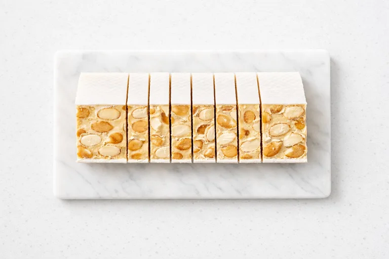 Sliced Turron de Alicante showing whole almonds in white honey nougat with wafer paper layers