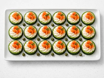 Smoked salmon cucumber canapes on a white serving platter with cream cheese, dill, and capers