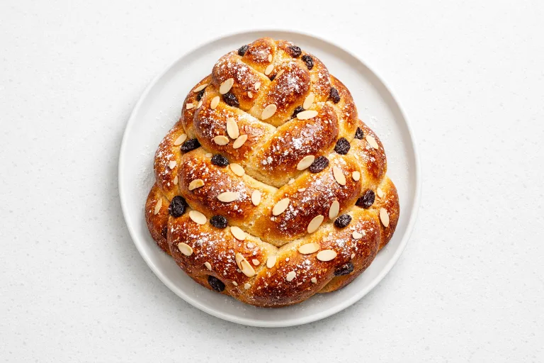 Traditional Czech vanocka Christmas braided bread with almonds and raisins on a white plate