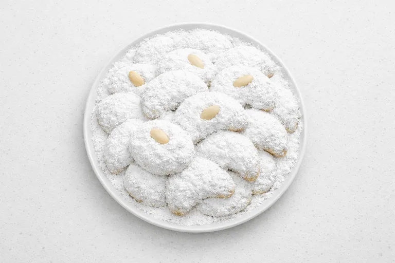 Traditional Greek kourabiedes Christmas butter and almond cookies dusted in powdered sugar on a white plate